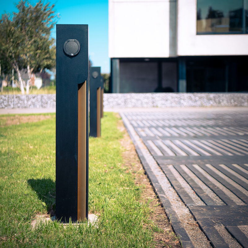 DSC 0201 expand 169 Two Veton charging stations on a lawn beside a modern building, socket outlet visible.